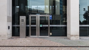 Une entrée d’immeuble avec une porte en verre, un portail métallique et une enseigne indiquant « pano » et « pano ramic ».