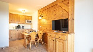 Una cocina de madera con comedor, que incluye una mesa, sillas, un microondas y un televisor.