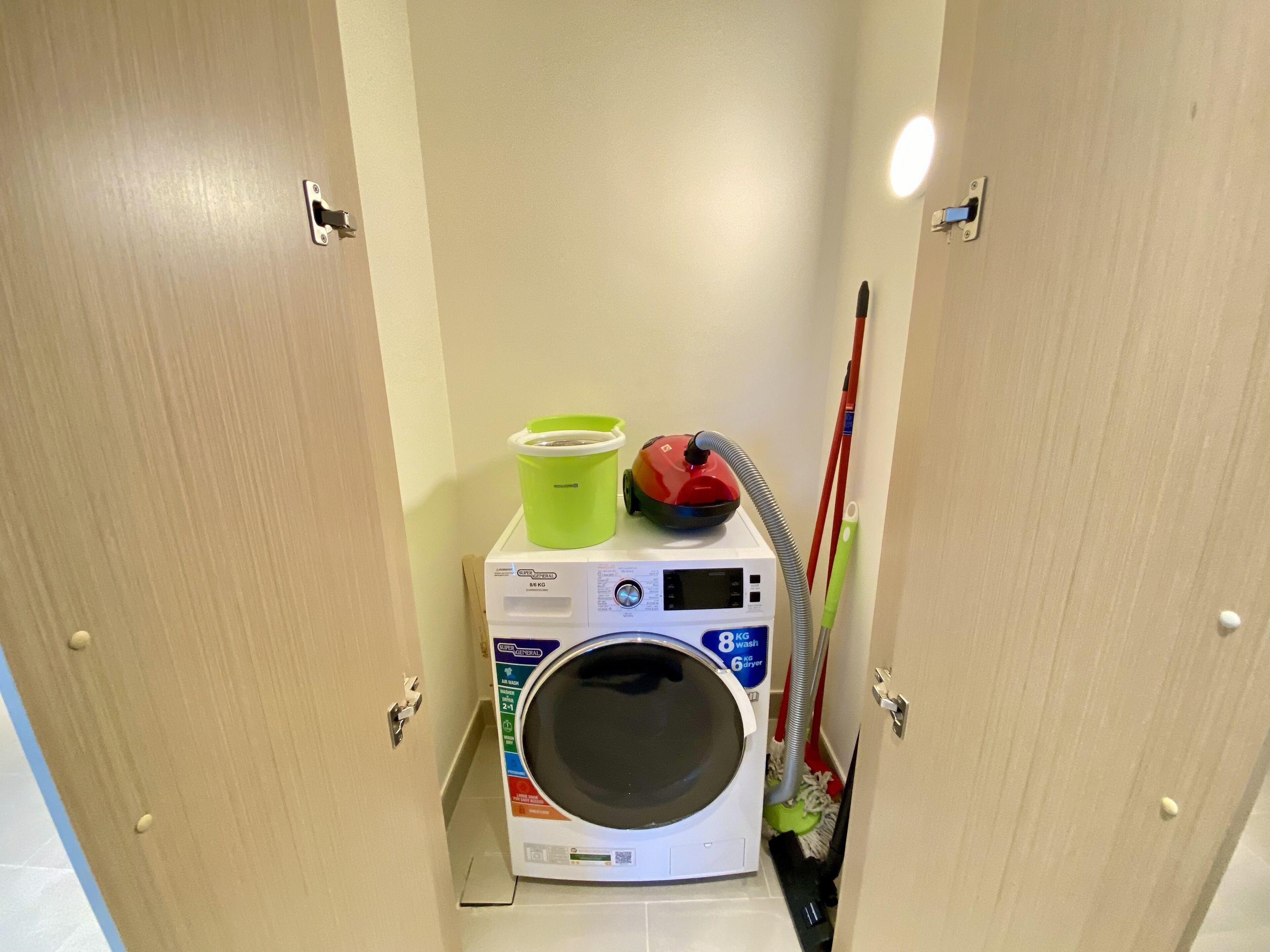 Ein kleiner Waschbereich mit Waschmaschine, Trockner und einem Mopp.