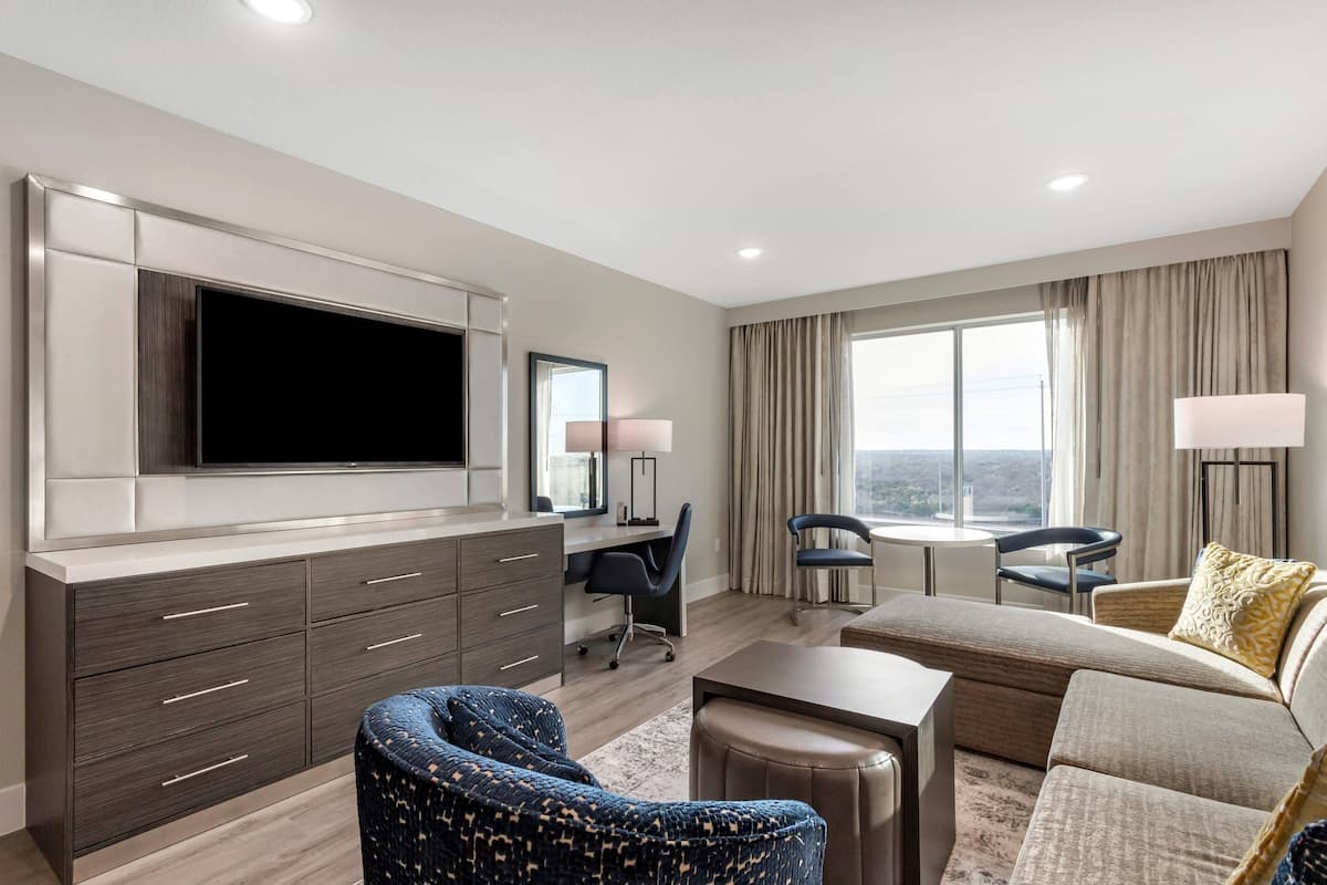 A modern hotel room with a flat-screen TV, a desk, a comfortable sofa, and a view of the city.