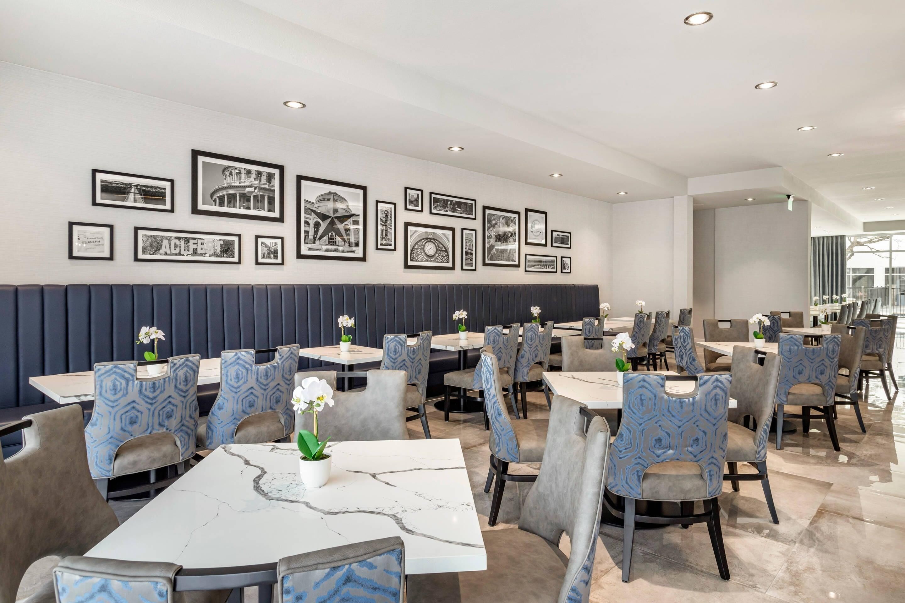 A modern dining area with marble tables, patterned chairs, and framed pictures on the wall.