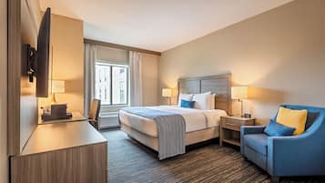 A hotel room with a bed, bedside tables, a desk, a chair, and a TV.