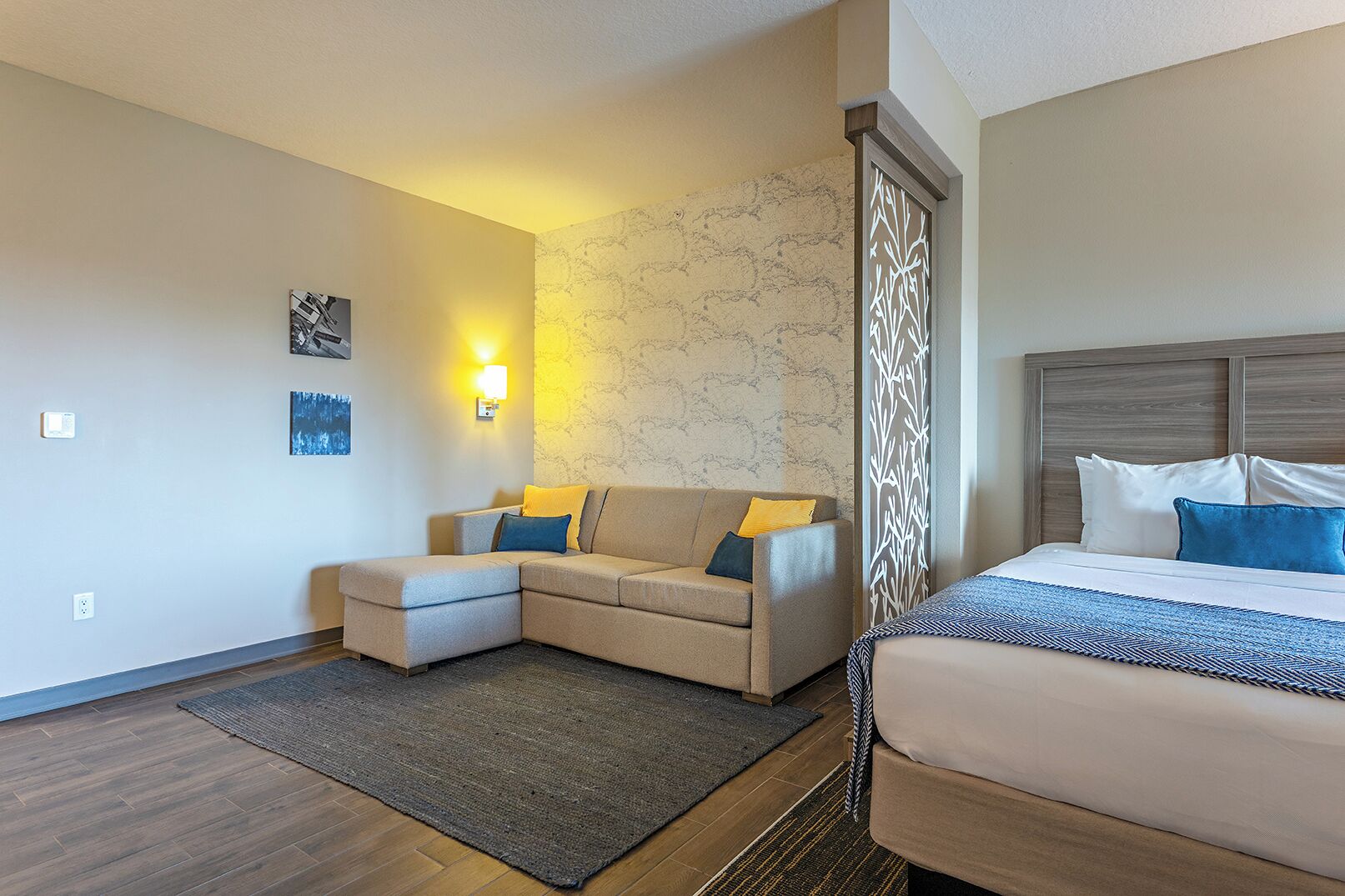 Ett hotellrum med en soffa, en säng, en vägg med mönster och en dekorativ skärm.
