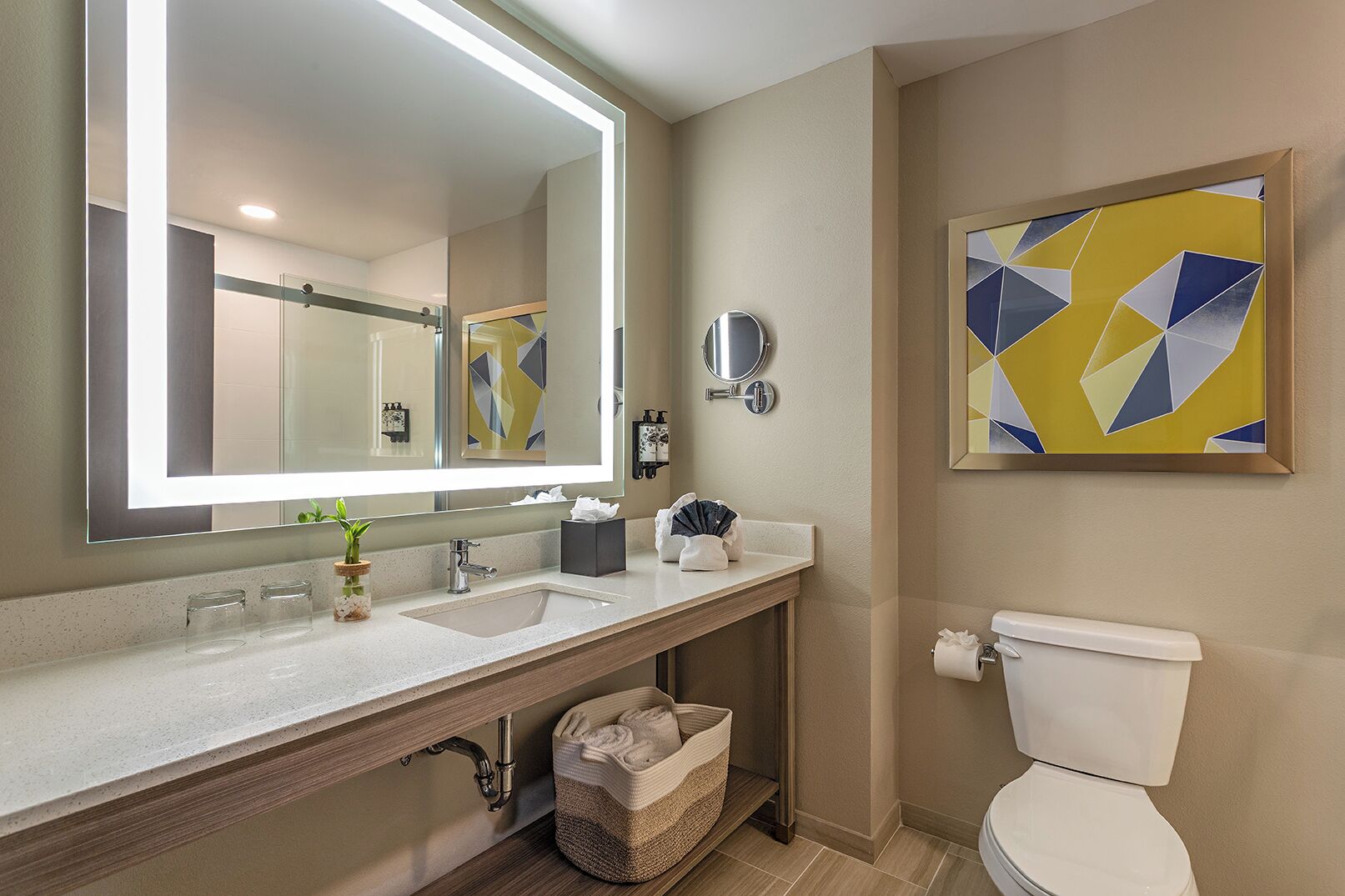 Une salle de bain avec un grand miroir, un lavabo, des toilettes et un porte-serviettes fixé au mur.