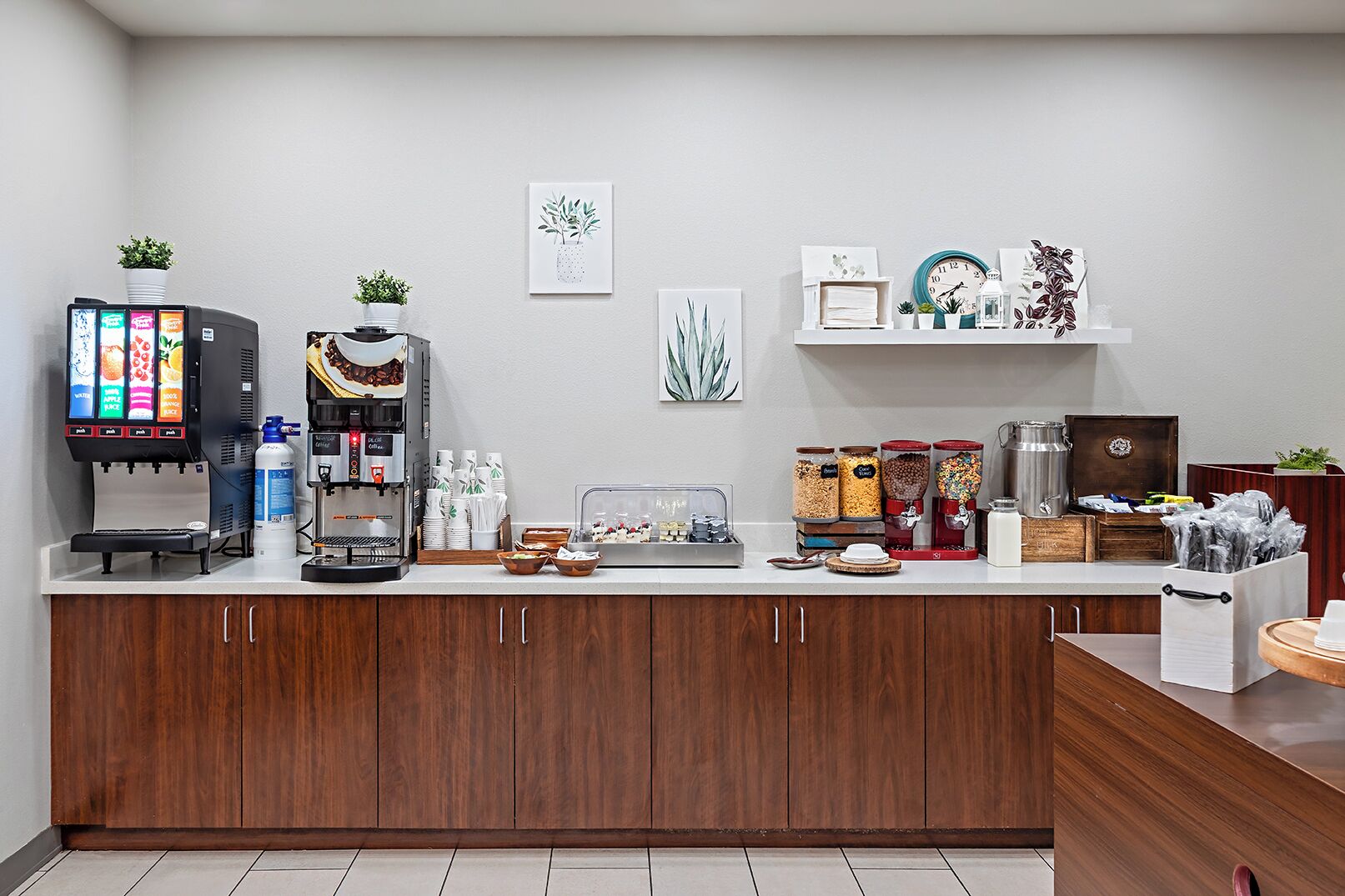 A modern kitchen with a coffee station, including a coffee machine, a tea station, and various food containers.