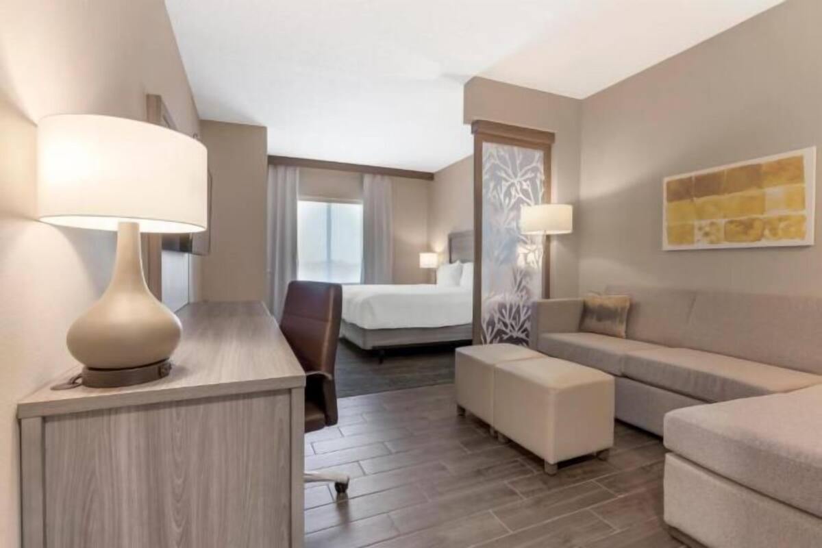 Une chambre d’hôtel avec un lit, un bureau doté d’une lampe, un canapé et une chaise.