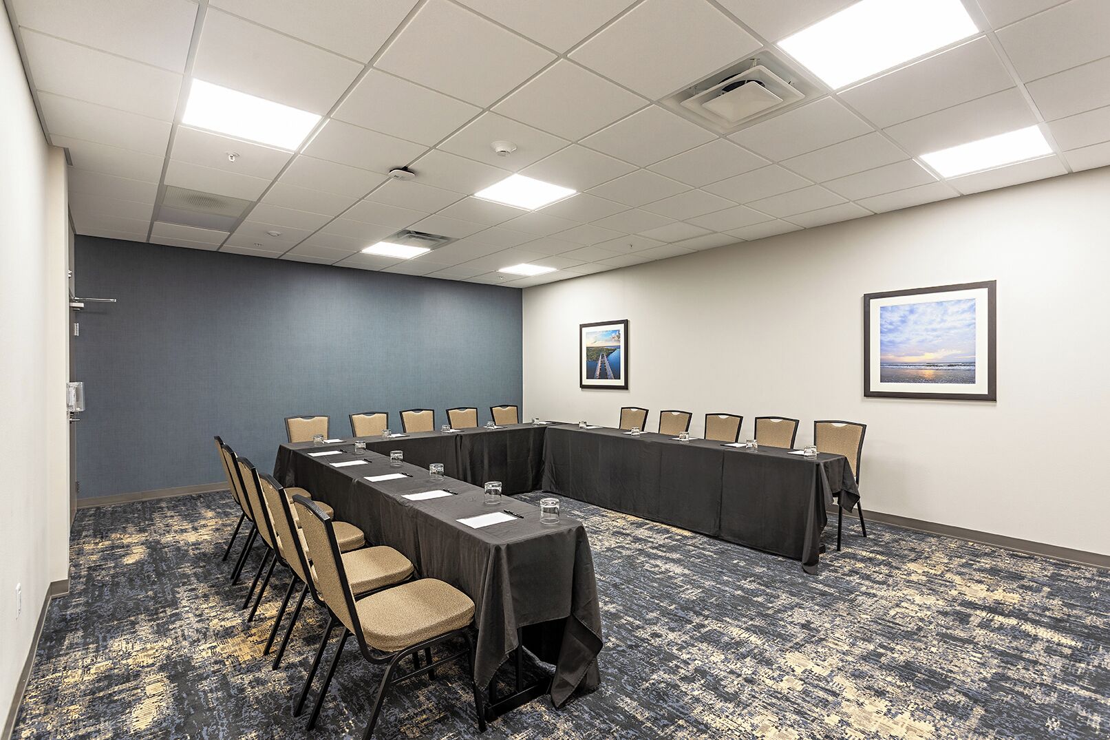 A conference room with a long table, chairs, and two framed pictures on the wall.