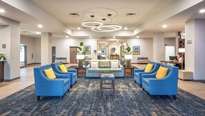 A spacious lobby with a central seating area, a reception desk, and a visible staircase leading to other floors.