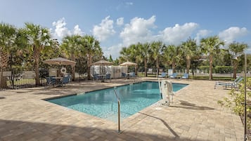 Una piscina al aire libre, sombrillas, sillones reclinables de piscina