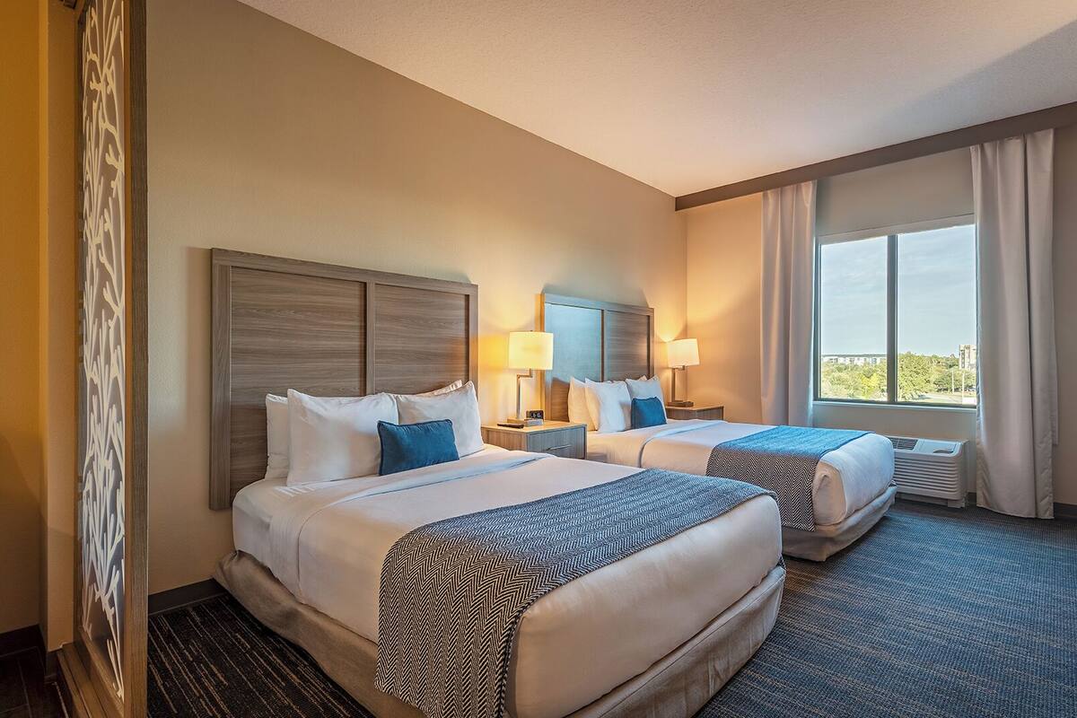 Une chambre d’hôtel avec deux lits, une grande fenêtre et une vue sur la ville.