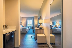 A hotel room with two beds, a desk, a chair, a mirror, and a minibar. - Pestana Orlando Suites - Lake Buena Vista (Orlando)