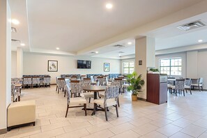 A spacious dining area with multiple tables and chairs, a reception desk, and a large window providing natural light. - Pestana Orlando Suites - Lake Buena Vista (Orlando)