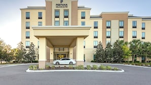 A hotel with a modern facade, a central entrance, and a parking area.