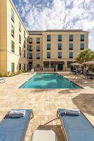 Una piscina al aire libre, sombrillas, sillones reclinables de piscina