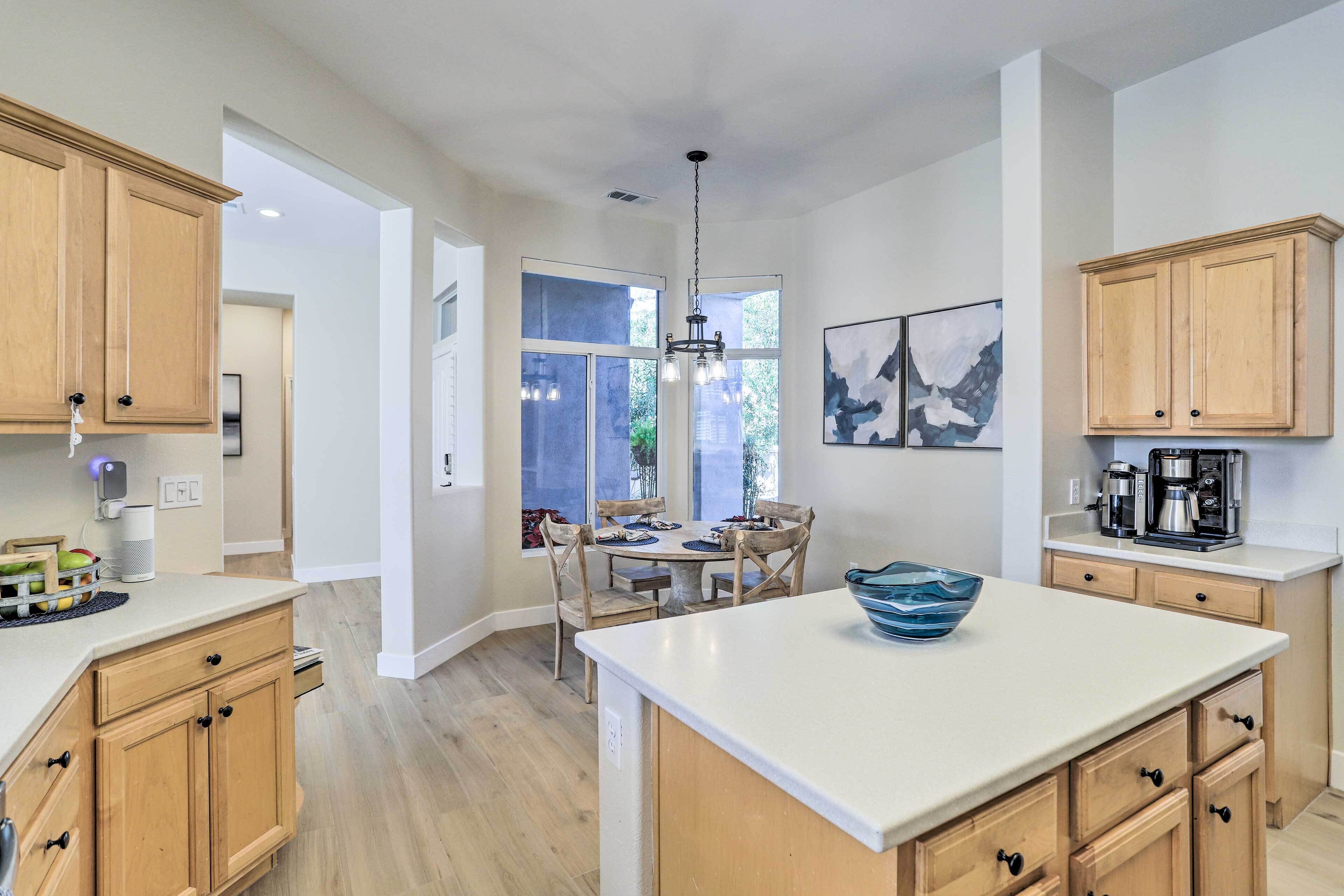 A modern kitchen with wooden cabinets, a central island, and a dining area with a table and chairs.