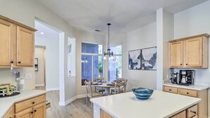 Une cuisine moderne avec des meubles en bois, un îlot central et un coin repas comprenant une table et des chaises.