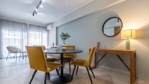 Zona pranzo con tavolo rotondo, sedie gialle, un tavolino in legno e uno specchio appeso al muro.