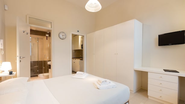 Hotellihuone, jossa on sänky, työpöytä, televisio ja vaatekaappi.
