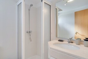 Un baño moderno con ducha, lavamanos y espejo.
