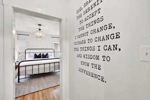 Un dormitorio con cama, candelabro y una cita motivacional en la pared.