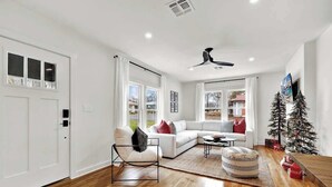 Un salon moderne avec un canapé blanc, un fauteuil noir, une table basse et un sapin de Noël.
