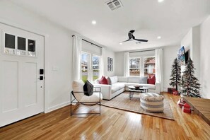 Una sala de estar moderna con un sofá blanco, una silla negra, una mesa de centro y un árbol de Navidad.