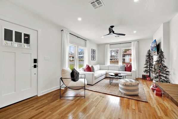 Una sala de estar moderna con un sofá blanco, una silla negra, una mesa de centro y un árbol de Navidad.