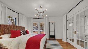 A modern bedroom with a large bed, a unique ceiling light fixture, and a view of the outside through a window.