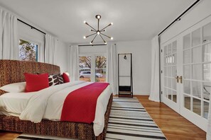 Un dormitorio moderno con una cama grande, una lámpara de techo original y vistas al exterior a través de una ventana.