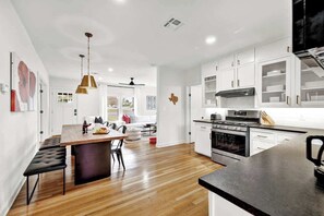 Una cocina moderna con armarios blancos, una isla central y un comedor con banco.