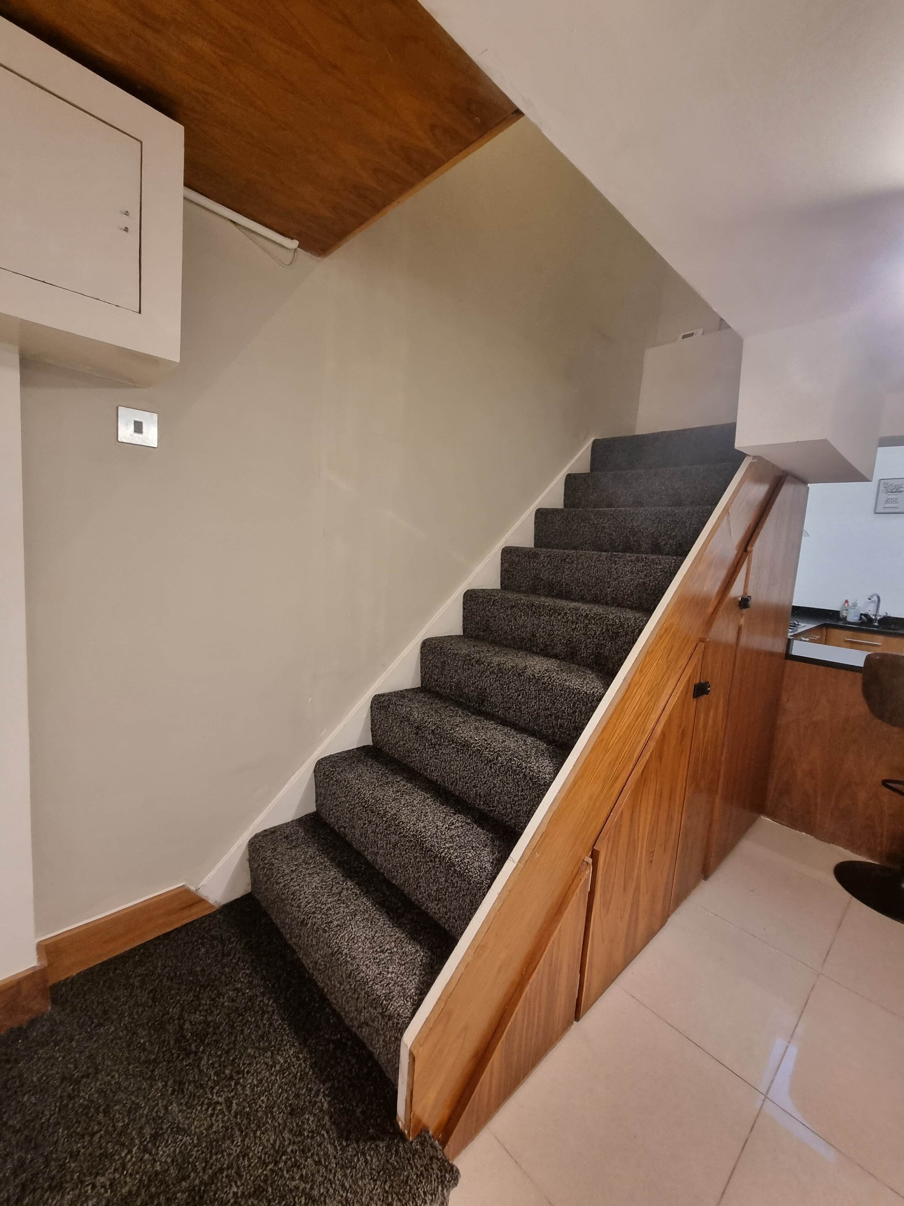 Una escalera con peldaños alfombrados que conduce a un rellano de madera.