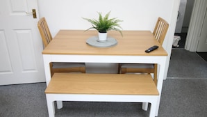 A small dining table with a potted plant, a remote control, and a bench. - Thesiger 1 (3 beds) (Cardiff)