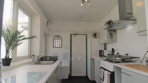 A compact kitchen with a sink, stove, microwave, and a small countertop. - Fitzroy Street (3 beds) (Cardiff)