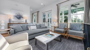 A modern living room with a grey sofa, two armchairs, a coffee table, and a bookshelf. - Gather. Laugh. Repeat. Luxury in BMB – Bikes Included, Golf Cart Available (Santa Rosa Beach)