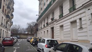 Eine enge Straße mit geparkten Autos und Häusern mit Balkonen.