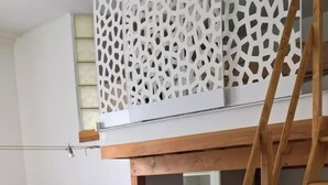 Eine kleine Küche mit einem integrierten Kühlschrank, einer Holzleiter und einer dekorativen weißen Wandverkleidung über der Arbeitsfläche.