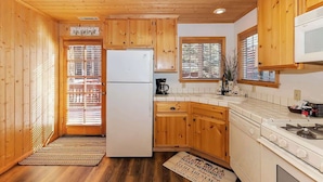 A compact kitchen with wooden cabinets, a white refrigerator, and a stove. - Hibernation Station I Near Snow Summit (Big Bear Lake)