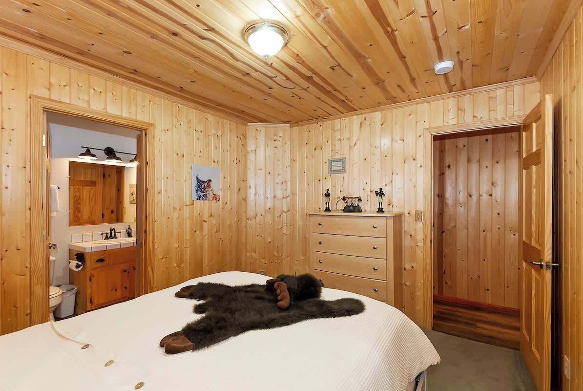 Une pièce aux murs lambrissés, contenant un lit, une commode et une porte.