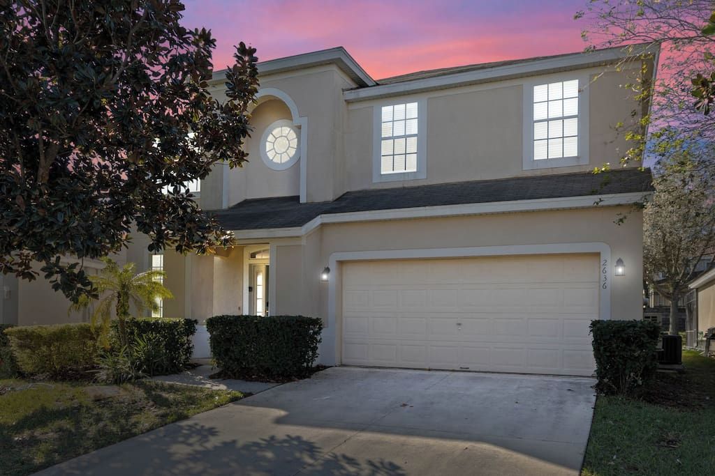 A two-story house with a garage, a circular window on the second floor, and a well-maintained front yard.