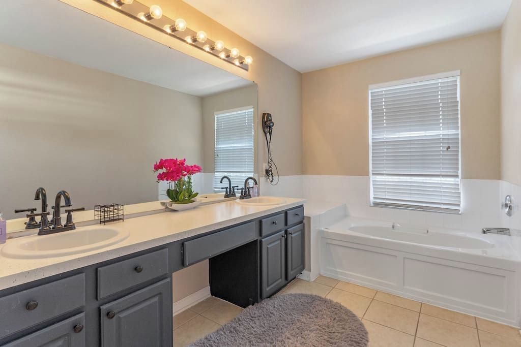 A modern bathroom with a double sink vanity, a large mirror, and a standalone bathtub.