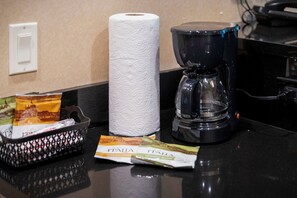 A hotel room counter with a coffee maker, a roll of toilet paper, and a basket containing a packet of tissues and a small item with 'ITALIA' branding. - MGM Signature Tower 2 | 8th Floor 2-Suite | Strip View Balcony | No Resort Fee (LAS VEGAS)