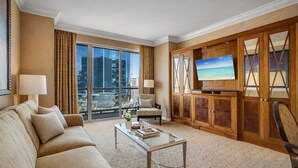 Ein Hotelzimmer mit großem Fenster, einer Couch, einem Fernseher und einem Schrank.