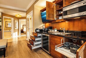 A modern kitchen with wooden cabinets, a stainless steel oven, and a built-in TV.