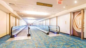 A hotel corridor with escalators, patterned carpet, and a sign indicating the direction to the MGM.