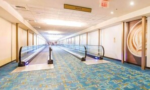 A hotel corridor with escalators, patterned carpet, and a sign indicating the direction to the MGM. - MGM Signature Tower 2 | 8th Floor 2-Suite | Strip View Balcony | No Resort Fee (LAS VEGAS)