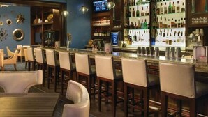 A bar area with multiple seating options, including bar stools and tables, and a well-stocked bar counter.