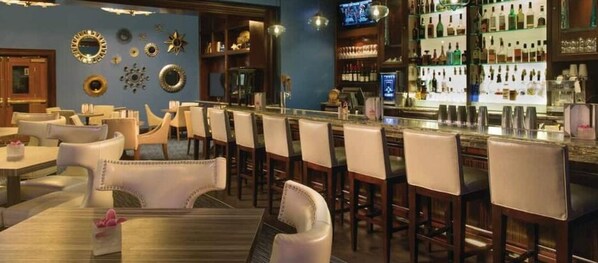 A bar area with multiple seating options, including bar stools and tables, and a well-stocked bar counter.