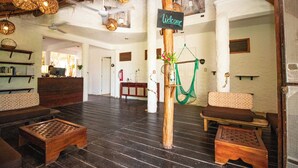 A spacious lobby with wooden flooring, wicker hanging lights, and a welcome sign. - Hotel Ak'Na Holbox (Isla Holbox)