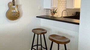 A kitchen with white cabinets, a black countertop, and two wooden stools. - Inner City TownHome (Fort Worth)