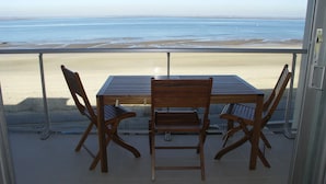 Un balcone con tavolo e sedie con vista sulla spiaggia.